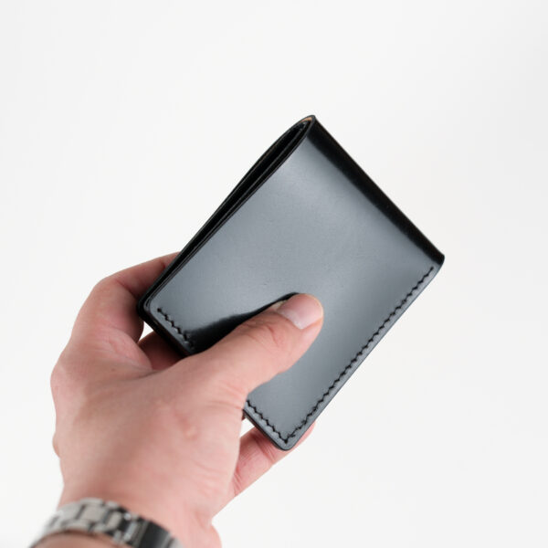 a male hand holding Shell cordovan wallet, black color.